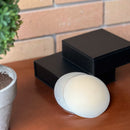 Cobre-mamilos de cor pele clara e duas caixas Nip No More sobre um aparador marrom com uma parede de tijolos ao fundo. Cobertura perfeita para qualquer roupa—compre agora!